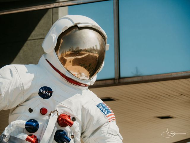 An astronaut sculpture outside the Gerald R. Ford Presidential Museum, its gold visor reflecting the museum grounds and blue sky