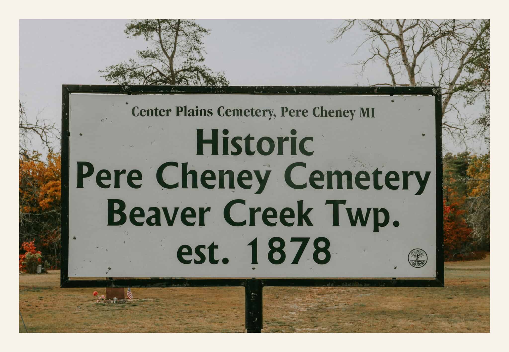 A weathered sign at the entrance to Pere Cheney Cemetery in Beaver Creek Township, Michigan, marking the site as historic and established in 1878.