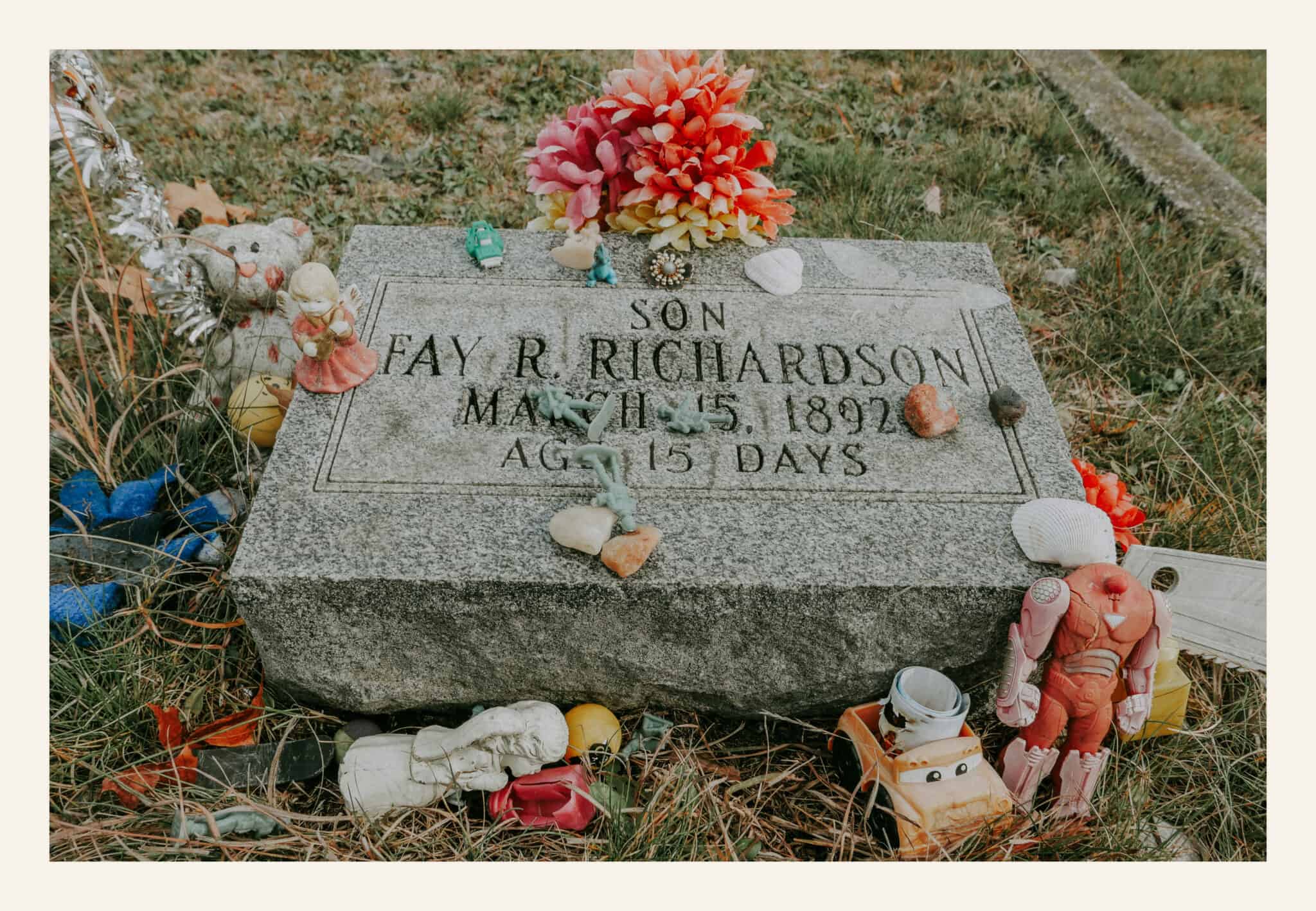The grave of Fay R. Richardson, aged 15 days, March 15, 1892, at Pere Cheney Cemetery, covered with toys, seashells, stones, and artificial flowers left by visitors.